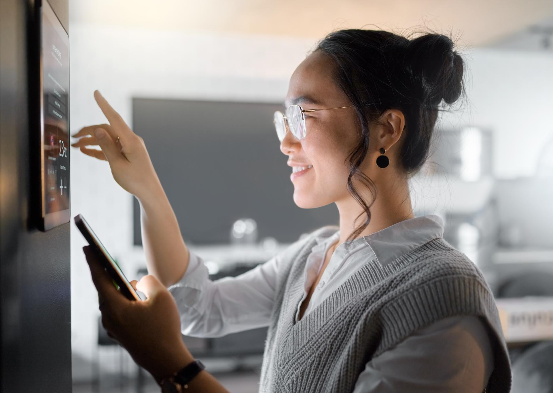 Smart home wall system, phone and woman with digital monitor for house automation, air conditioning or safety security network. App software, ui dashboard panel and Asian girl programming IOT tech