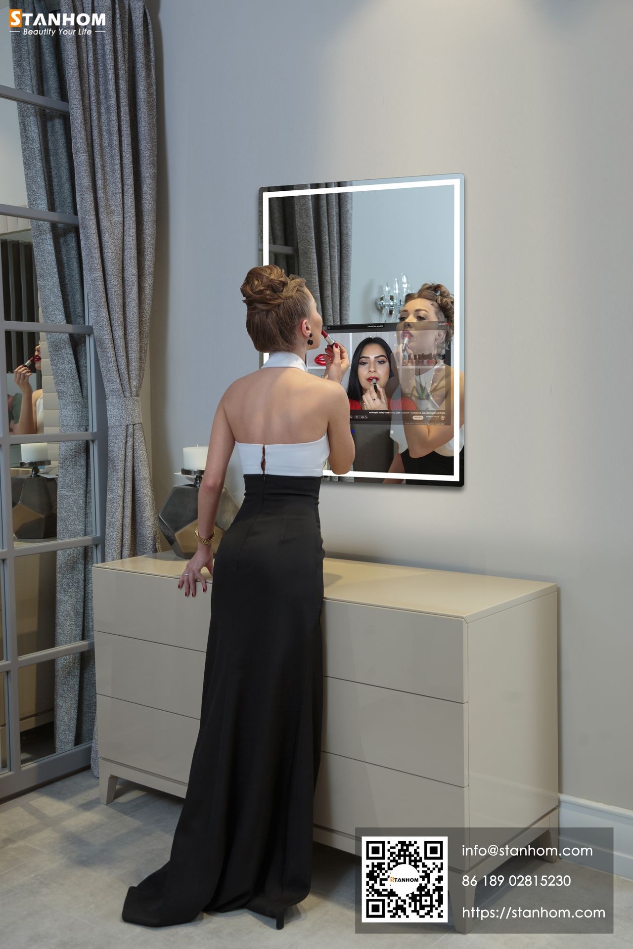 Woman in elegant dress applying lipstick in front of mirror with soft lighting and modern decor.