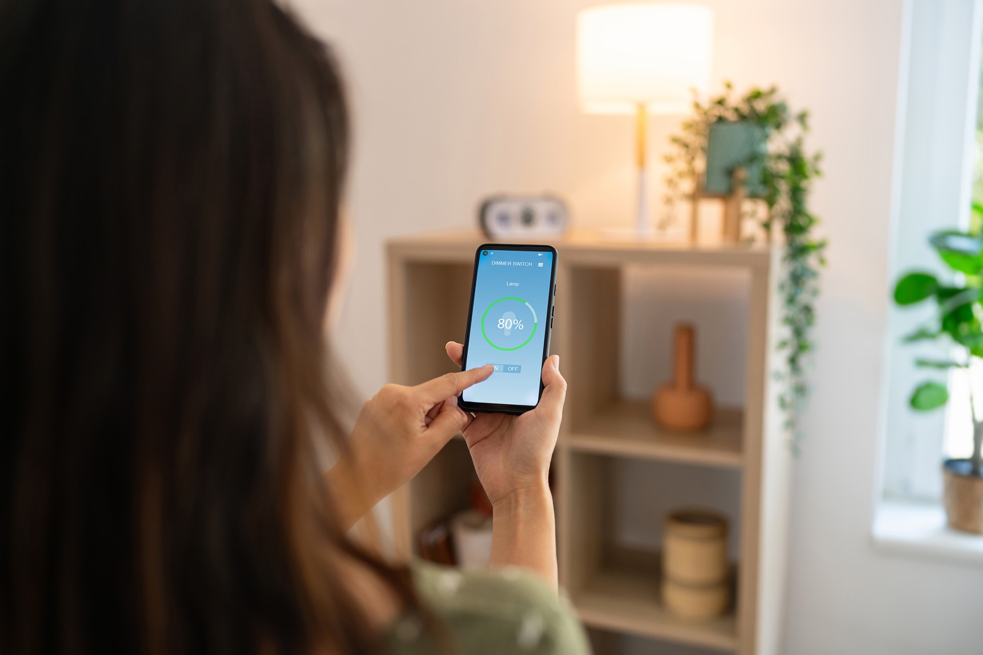 Woman controlling light with a smart phone at home